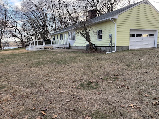 exterior space with a lawn, a deck with water view, and a garage