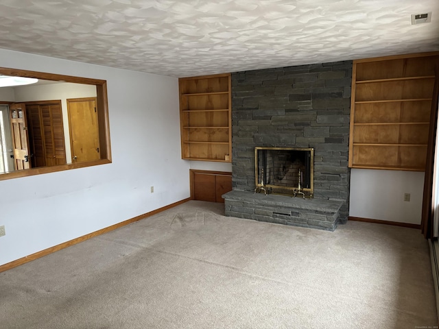 unfurnished living room featuring built in shelves, a stone fireplace, light colored carpet, and a textured ceiling