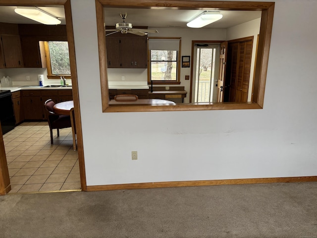 kitchen featuring dark brown cabinets, light colored carpet, ceiling fan, and a healthy amount of sunlight