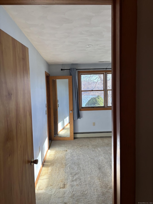 hall featuring light carpet and a baseboard heating unit