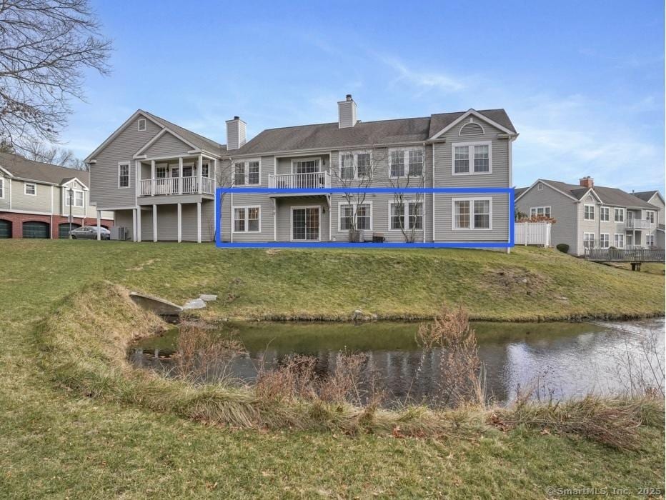 rear view of house with a lawn and a water view