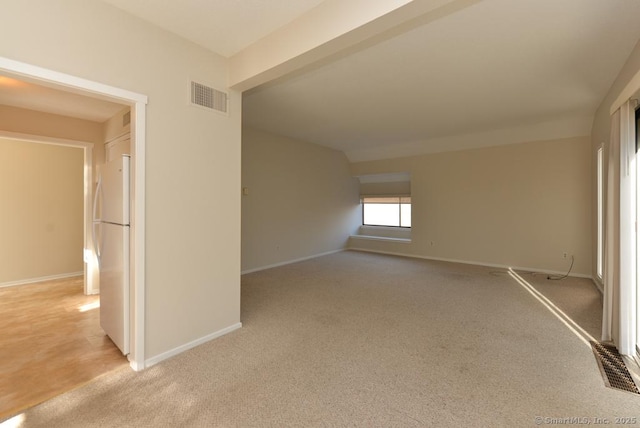 empty room featuring light carpet and vaulted ceiling with beams