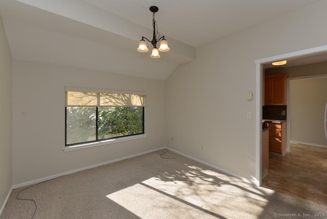 spare room featuring carpet flooring, a chandelier, and lofted ceiling