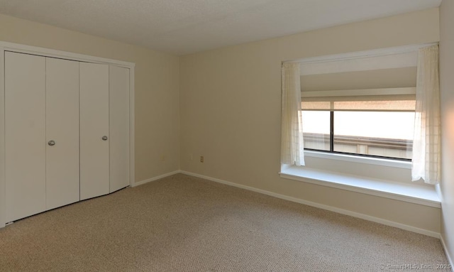 unfurnished bedroom featuring light colored carpet and a closet