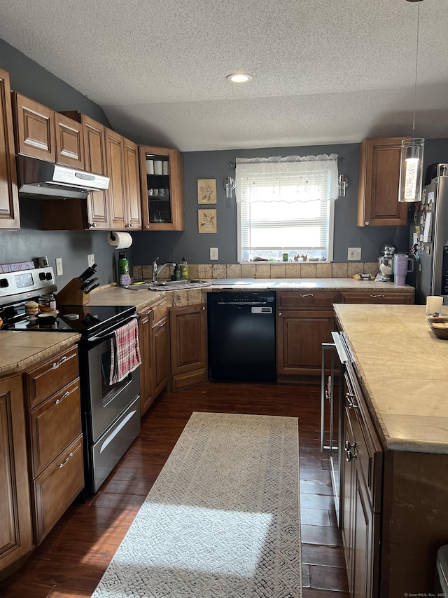 kitchen with appliances with stainless steel finishes, a textured ceiling, dark wood-type flooring, sink, and decorative light fixtures