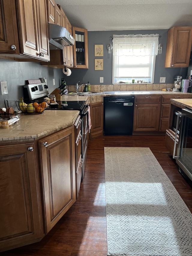 kitchen featuring dishwasher, dark wood-type flooring, sink, a textured ceiling, and stainless steel range