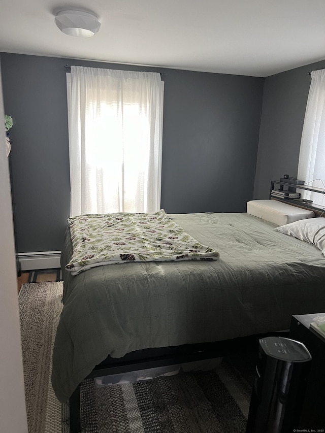 bedroom featuring hardwood / wood-style flooring and a baseboard heating unit