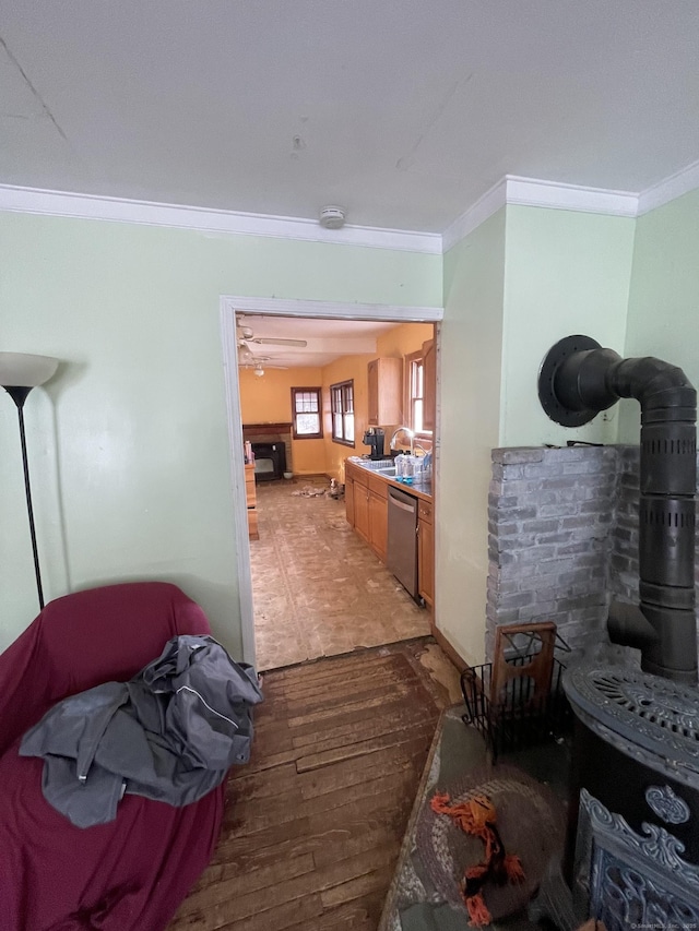 kitchen with hardwood / wood-style floors, sink, a wood stove, stainless steel dishwasher, and crown molding