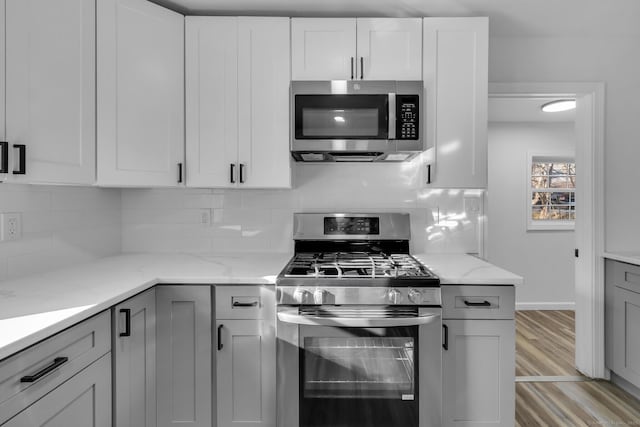 kitchen with white cabinetry, tasteful backsplash, appliances with stainless steel finishes, and light stone counters