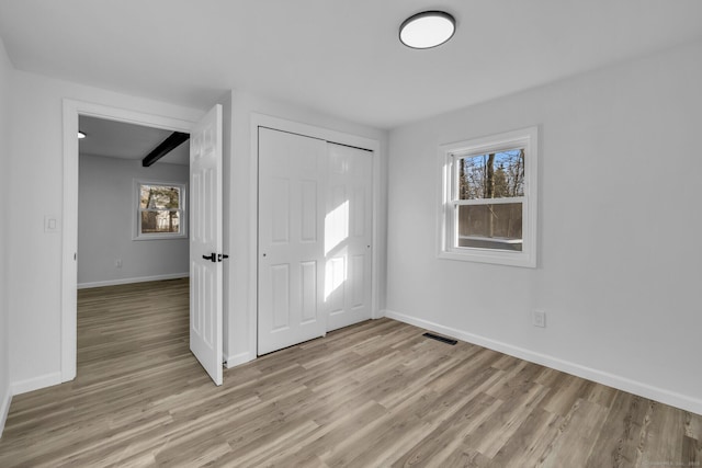 foyer with a wealth of natural light, light hardwood / wood-style floors, and beamed ceiling