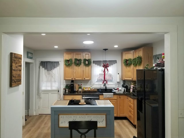 kitchen featuring black fridge with ice dispenser, light hardwood / wood-style flooring, pendant lighting, sink, and light brown cabinets