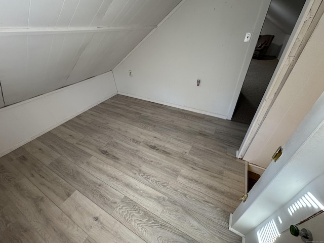 additional living space featuring light wood-type flooring and vaulted ceiling