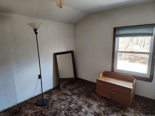 unfurnished room featuring vaulted ceiling and dark carpet