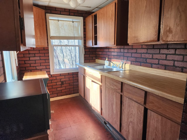 kitchen featuring brick wall, a paneled ceiling, and sink