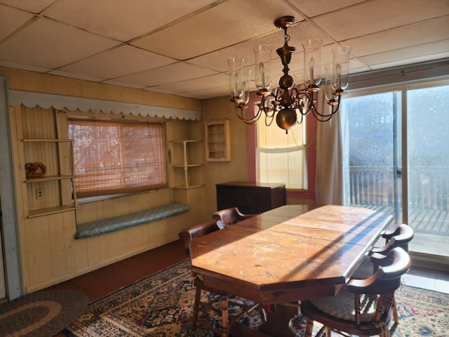 dining space with an inviting chandelier, a drop ceiling, and hardwood / wood-style floors