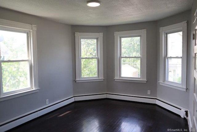 empty room featuring a wealth of natural light, hardwood / wood-style floors, a baseboard radiator, and a textured ceiling