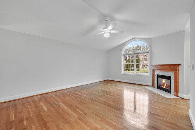 unfurnished living room with vaulted ceiling, ceiling fan, a fireplace, and light hardwood / wood-style flooring