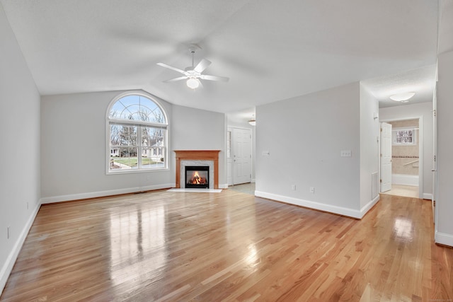 unfurnished living room featuring lofted ceiling, ceiling fan, light wood-type flooring, and a premium fireplace