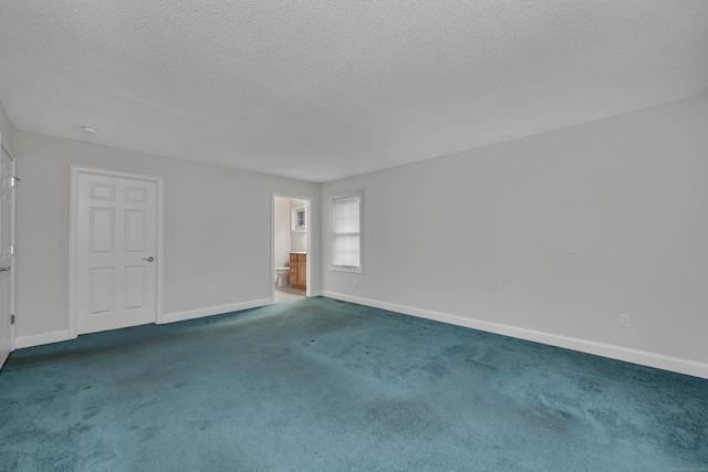 spare room featuring a textured ceiling and dark colored carpet