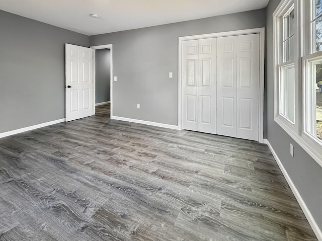 unfurnished bedroom with dark hardwood / wood-style floors and a closet