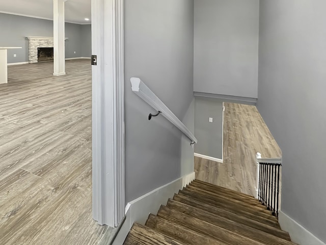 staircase with a stone fireplace and hardwood / wood-style floors