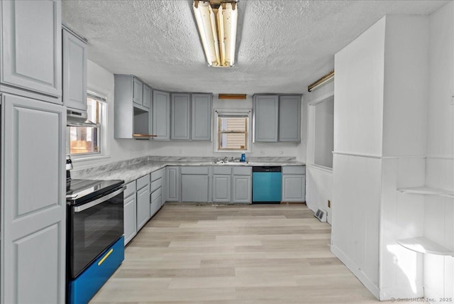 kitchen featuring gray cabinets, a textured ceiling, range hood, light hardwood / wood-style floors, and stainless steel appliances