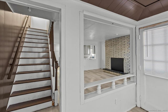 stairway with a healthy amount of sunlight, wood ceiling, and a fireplace