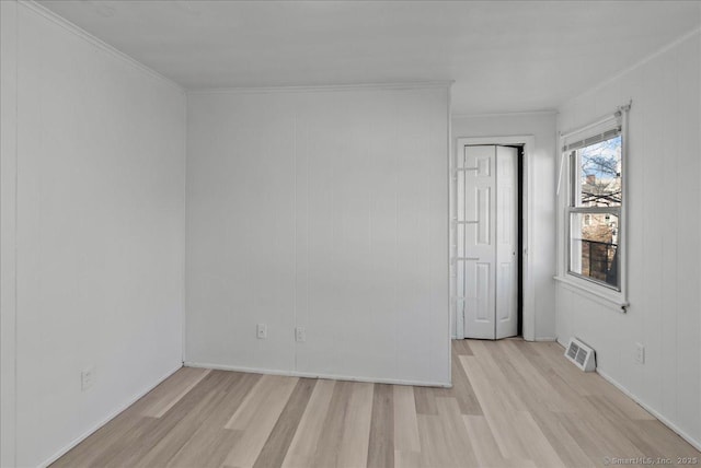 spare room with light wood-type flooring and crown molding