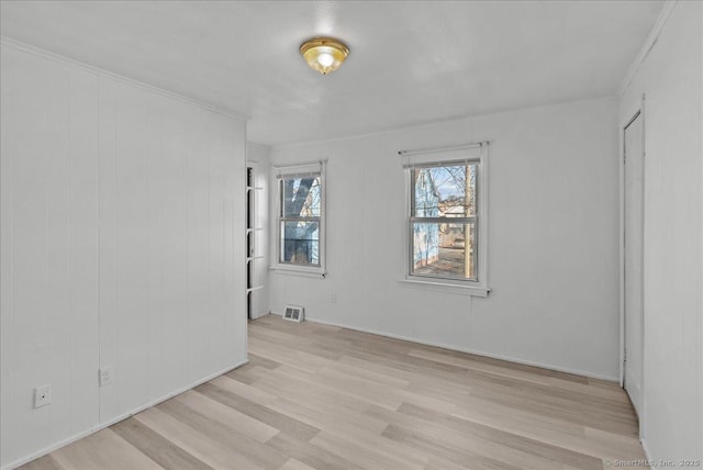 unfurnished room with ornamental molding and light wood-type flooring