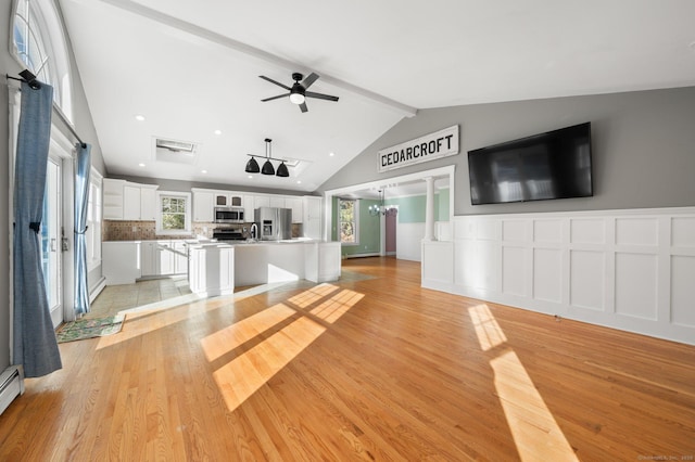 unfurnished living room with ceiling fan with notable chandelier, lofted ceiling with beams, light wood-type flooring, and a baseboard radiator