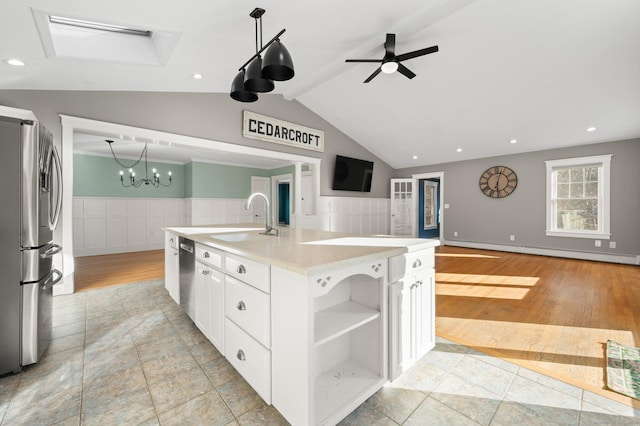 kitchen featuring stainless steel appliances, baseboard heating, sink, a center island with sink, and white cabinetry