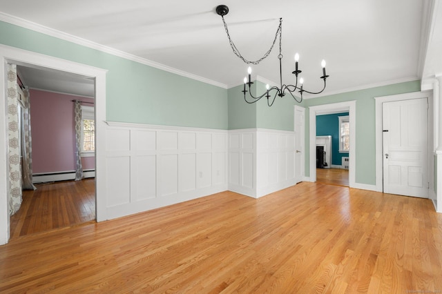 unfurnished dining area featuring ornamental molding, light wood-type flooring, and a baseboard heating unit