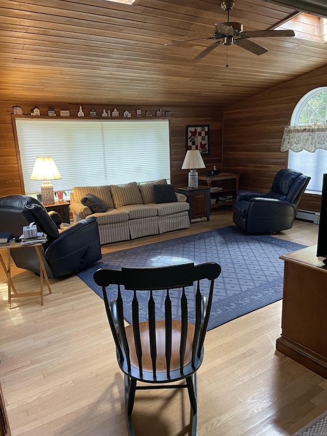 living room featuring wood walls, wooden ceiling, baseboard heating, ceiling fan, and light hardwood / wood-style floors