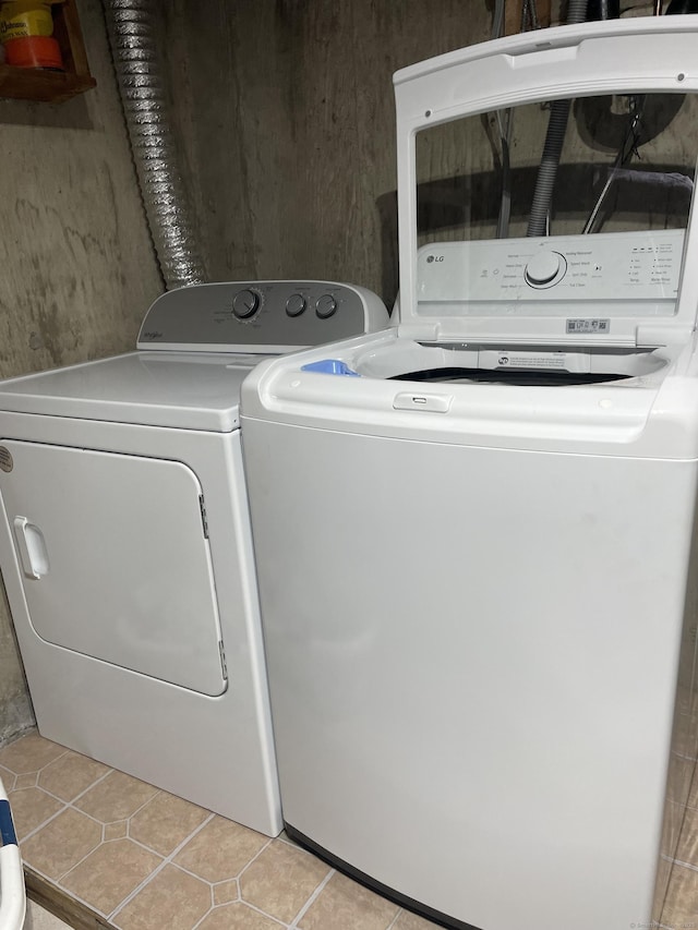 clothes washing area with light tile patterned floors and washer and clothes dryer