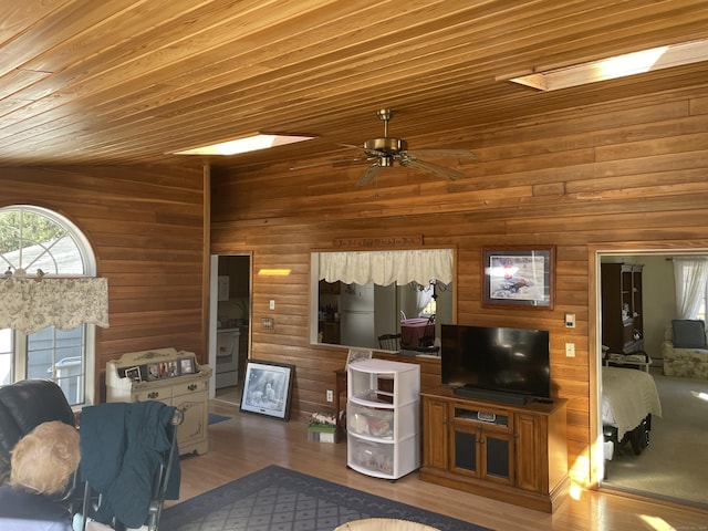 living room featuring hardwood / wood-style floors, ceiling fan, vaulted ceiling with skylight, and wood ceiling