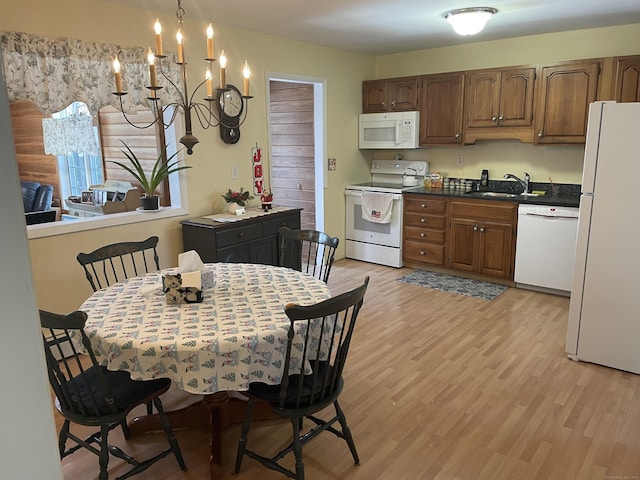 kitchen with a notable chandelier, sink, white appliances, and light hardwood / wood-style floors