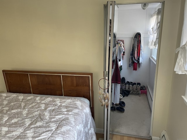 bedroom featuring hardwood / wood-style flooring, a closet, and a baseboard heating unit