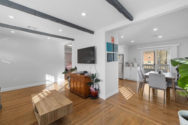 living room with light hardwood / wood-style flooring and beamed ceiling