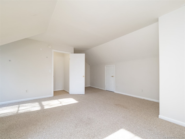 additional living space featuring light colored carpet and vaulted ceiling