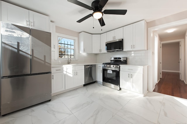 kitchen with appliances with stainless steel finishes, tasteful backsplash, ceiling fan, sink, and white cabinetry