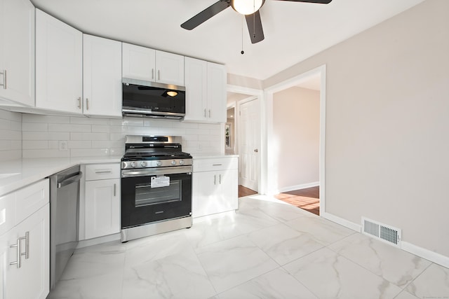 kitchen featuring white cabinets, stainless steel appliances, tasteful backsplash, and ceiling fan