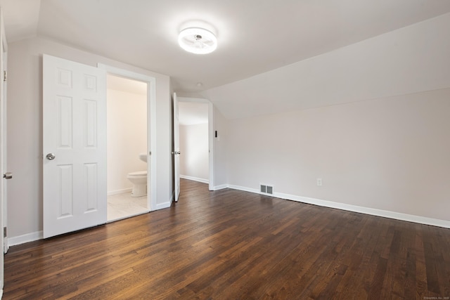 unfurnished bedroom with dark hardwood / wood-style flooring, ensuite bathroom, and lofted ceiling