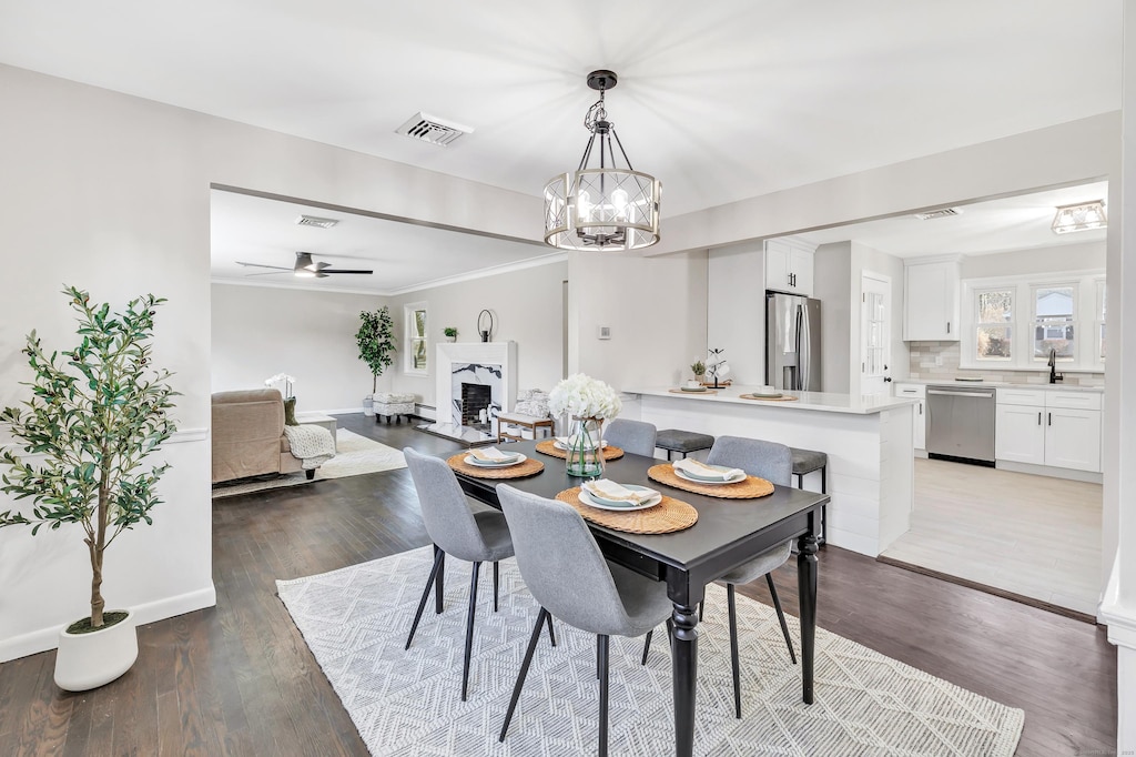 dining room with hardwood / wood-style floors, ceiling fan with notable chandelier, and sink