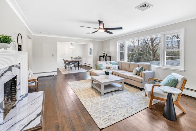 living room featuring hardwood / wood-style floors, a fireplace, ornamental molding, and a baseboard heating unit