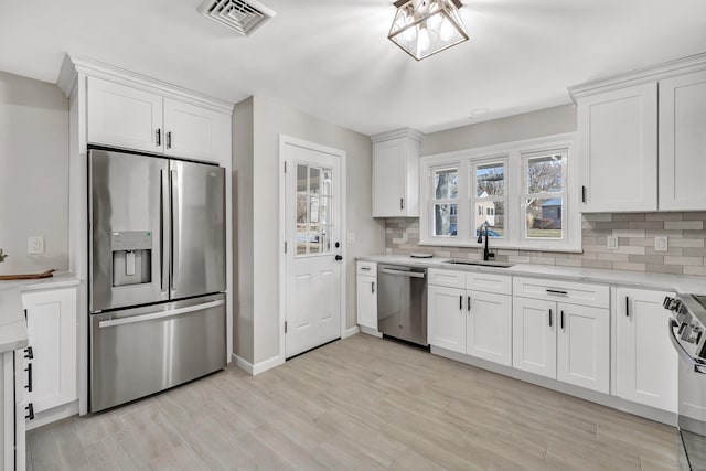 kitchen with appliances with stainless steel finishes, white cabinetry, and sink