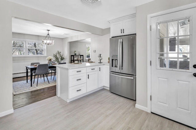 kitchen featuring kitchen peninsula, stainless steel refrigerator with ice dispenser, decorative light fixtures, light hardwood / wood-style floors, and white cabinetry