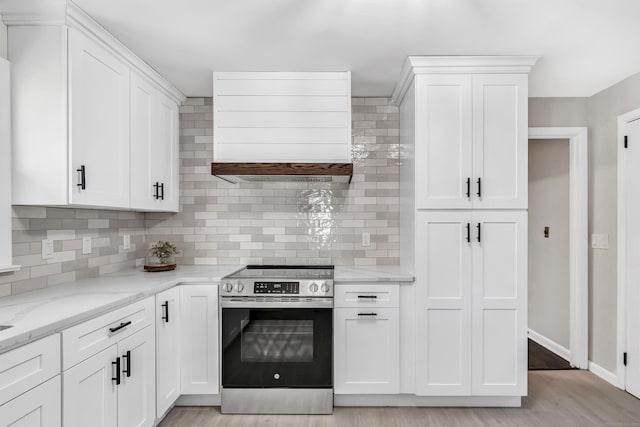 kitchen featuring tasteful backsplash, white cabinetry, stainless steel range, and extractor fan