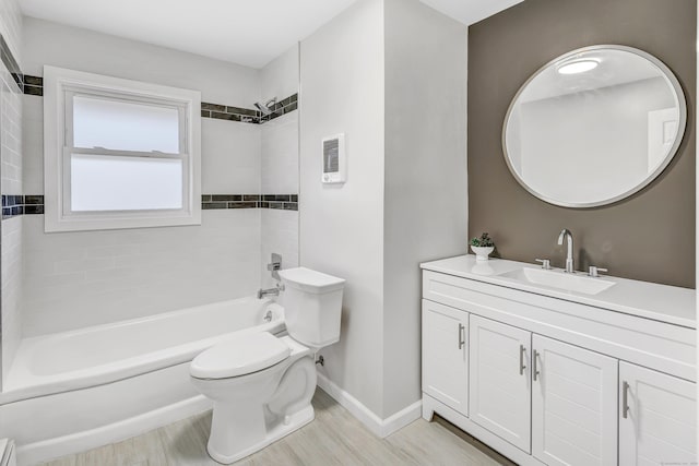 full bathroom featuring vanity, hardwood / wood-style floors, tiled shower / bath combo, and toilet