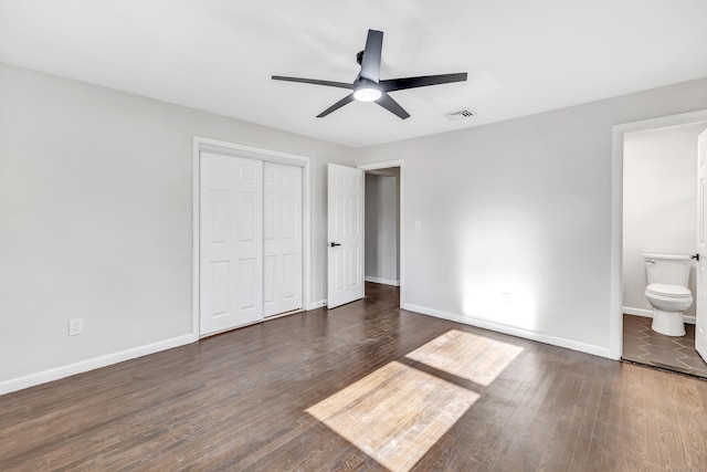 unfurnished bedroom with ensuite bath, ceiling fan, a closet, and dark hardwood / wood-style flooring