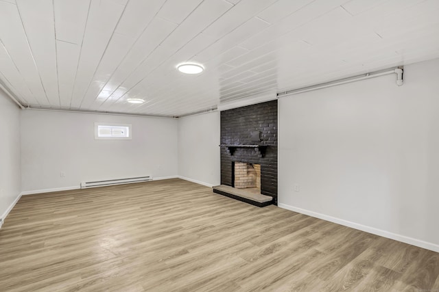 basement featuring baseboard heating, light hardwood / wood-style flooring, wooden ceiling, and a brick fireplace